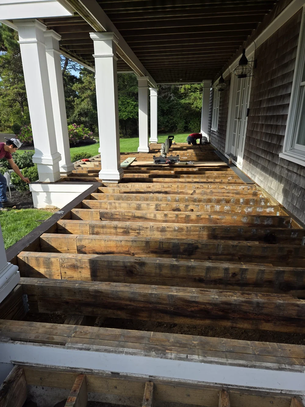 SHC deck repair in progress, with exposed floor framing beneath white porch columns