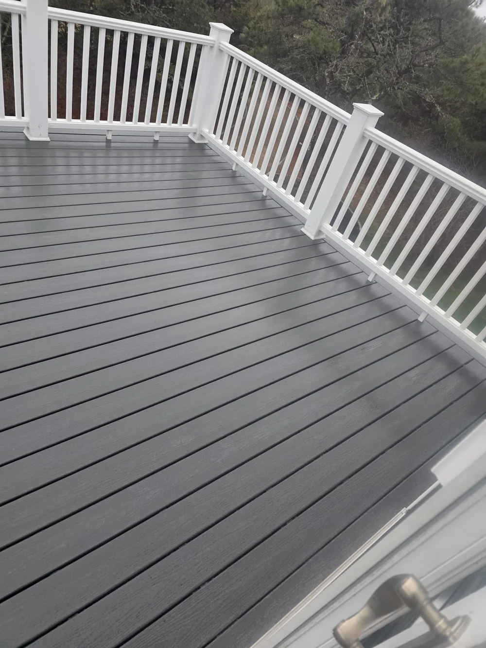 Finished upstairs deck corner with gray decking neatly meeting the white railing posts