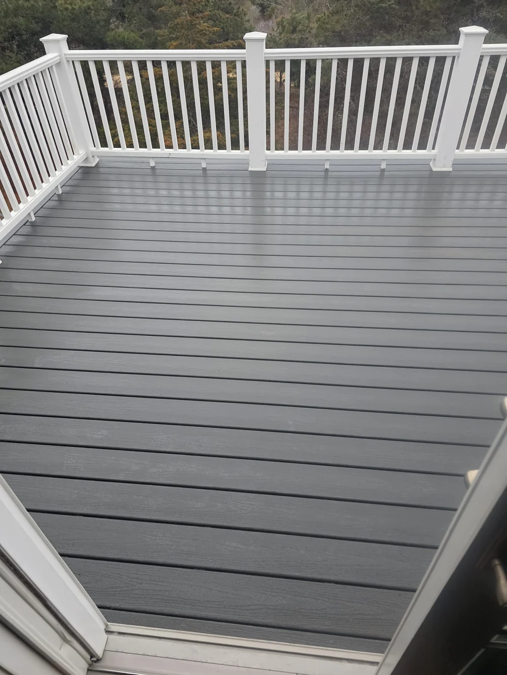Finished upstairs deck with gray boards and white railings, viewed through the doorway