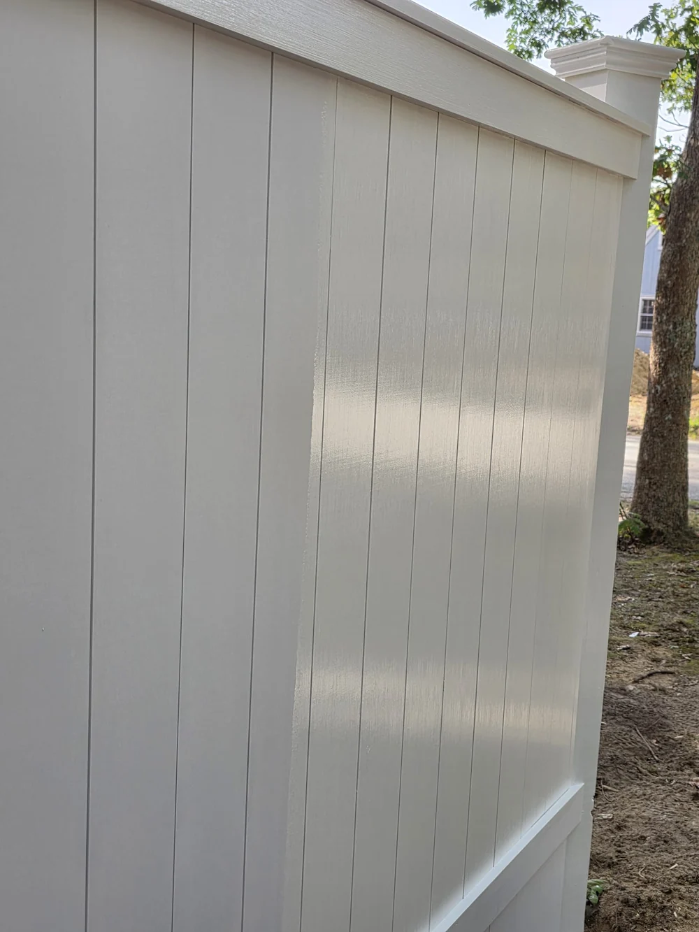 Close-up of white vertical fence boards, horizontal trim and a layered post cap