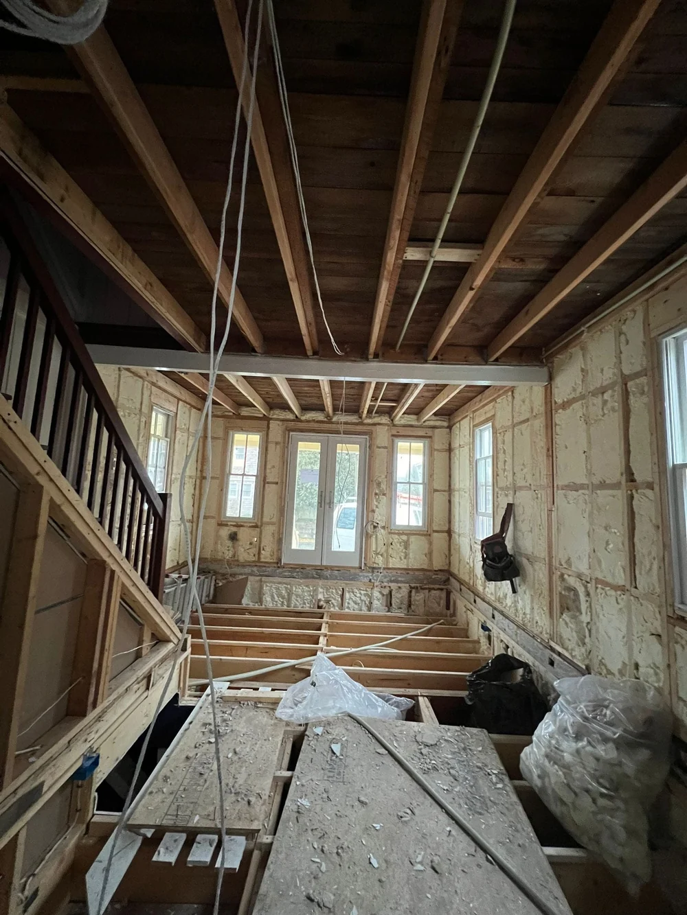 Before renovation: exposed floor and ceiling framing, open walls and wiring beside the original staircase